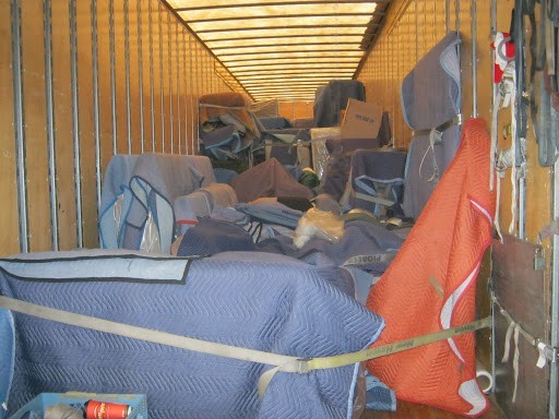 Various furniture convered with moving blankets inside a moving truck